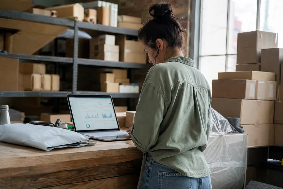Online store owner checking ad results on a laptop at her packing table