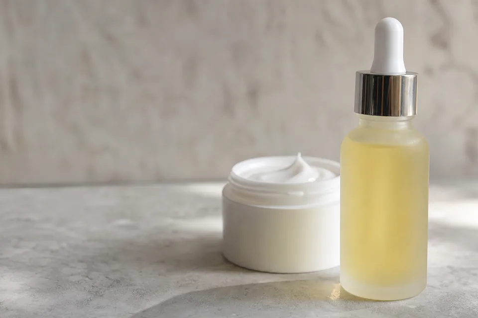 Skincare product photo of a serum bottle and a jar of cream on a stone surface, as used in a catalog ad